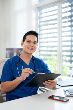 Portrait of smiling male doctor in scrubs with stethoscope in the medical office.