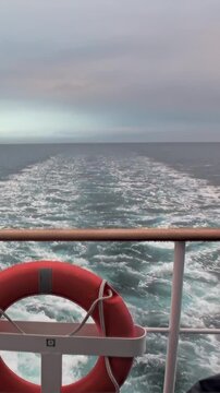 Gazing astern from a navigating vessel on the Arctic Ocean. The ship's passage creates a beautiful, white, foamy wake trailing across the deep, cool waters.