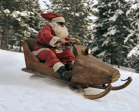 Santa Claus wearing sunglasses driving a custom wooden snowmobile downhill on snow