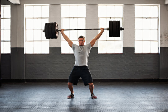 Fitness, weight training or man in gym with barbell, power or intense workout in bodybuilding. Exercise, endurance or athlete with equipment, lifting challenge or strength for muscle transformation.