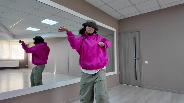 Young Woman in Pink Hoodie and Bucket Hat Dancing Freestyle in a Modern Apartment