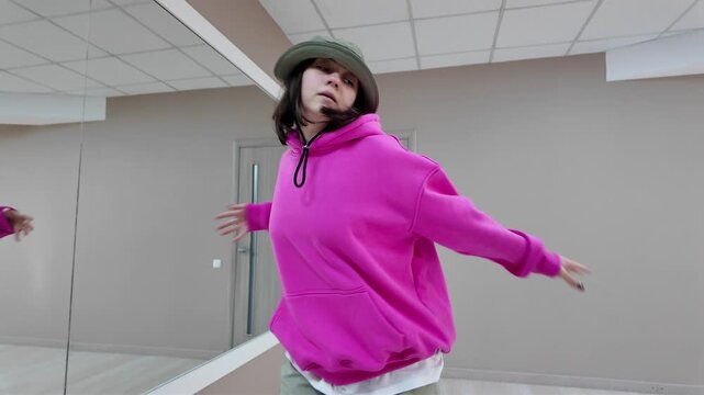 Young Woman in Pink Hoodie and Bucket Hat Dancing Freestyle in a Modern Apartment