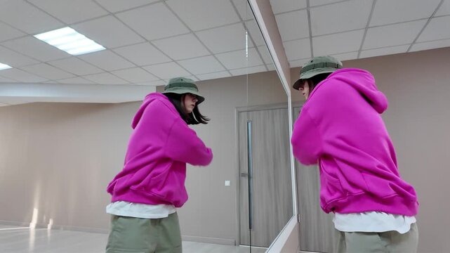 Young Woman in Pink Hoodie and Bucket Hat Dancing Freestyle in a Modern Apartment