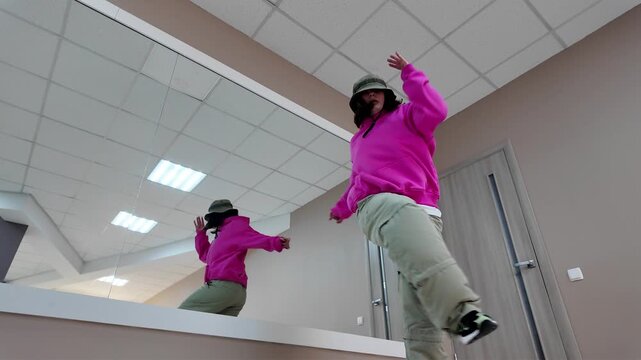 Young Woman in Pink Hoodie and Bucket Hat Dancing Freestyle in a Modern Apartment