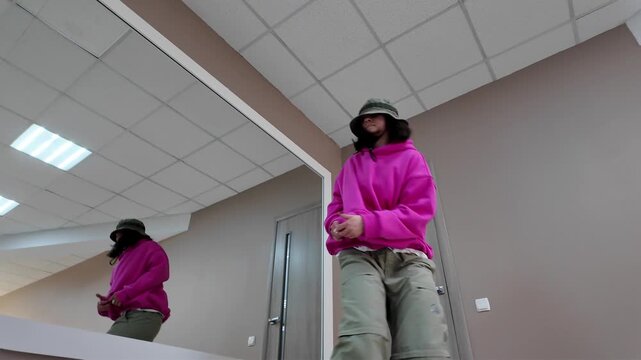 Young Woman in Pink Hoodie and Bucket Hat Dancing Freestyle in a Modern Apartment
