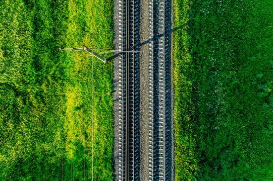 Railway tracks lined with gravel and green vegetation under bright sunlight