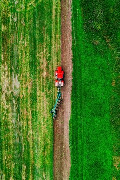 Tractor plowing a lush green field with earthy soil showing distinct plow lines