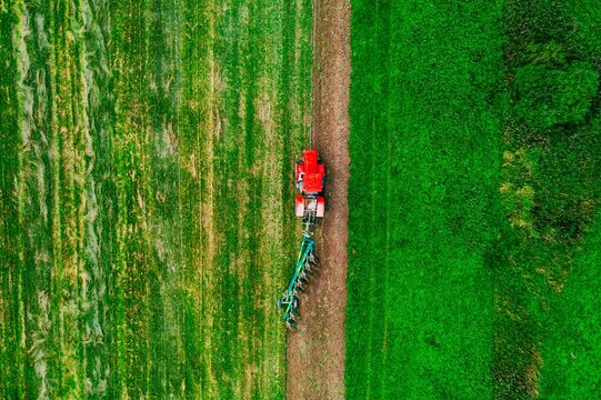 Tractor plowing lush green farmland in vibrant growing season under clear blue sky