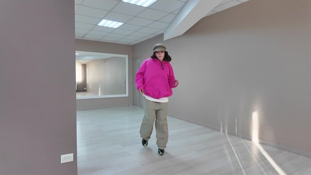 Young Woman in Pink Hoodie and Bucket Hat Dancing Freestyle in a Modern Apartment