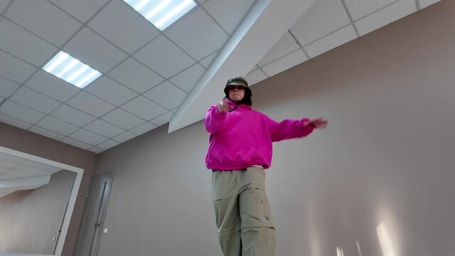 Young Woman in Pink Hoodie and Bucket Hat Dancing Freestyle in a Modern Apartment