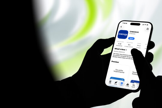 Kiel, Germany - 08-20-2026: Smartphone displaying the CHECK24 online comparison and financial services platform in the App Store, held by silhouetted hands with blurred background