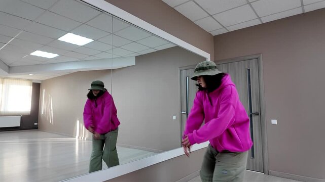 Young Woman in Pink Hoodie and Bucket Hat Dancing Freestyle in a Modern Apartment