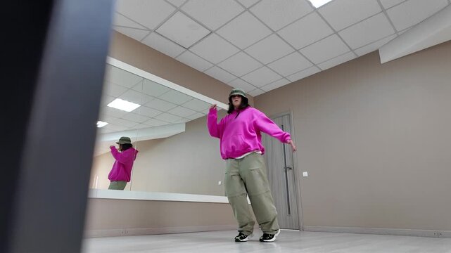 Young Woman in Pink Hoodie and Bucket Hat Dancing Freestyle in a Modern Apartment