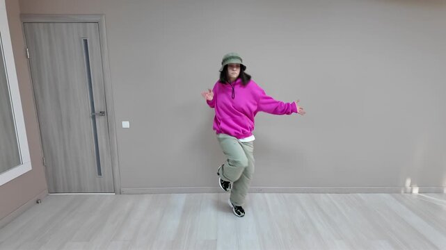 Young Woman in Pink Hoodie and Bucket Hat Dancing Freestyle in a Modern Apartment