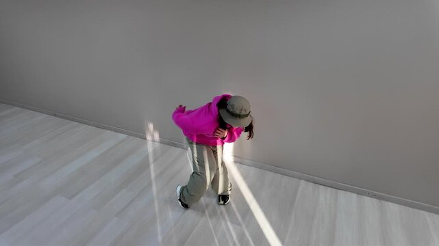 Young Woman in Pink Hoodie and Bucket Hat Dancing Freestyle in a Modern Apartment