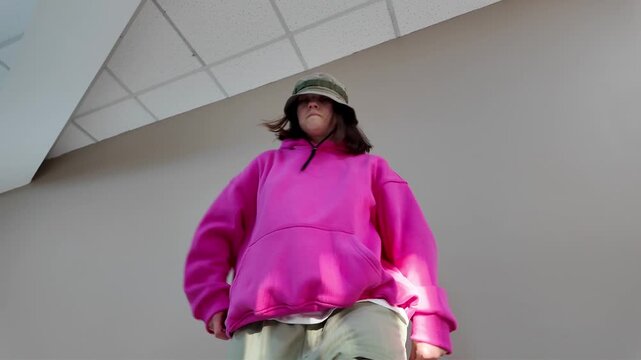 Young Woman in Pink Hoodie and Bucket Hat Dancing Freestyle in a Modern Apartment