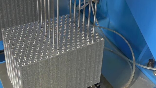 Precision drill bits descend into heavy metallic structures within a bright factory workshop to create perfect aligned holes for engineering components during a morning shift