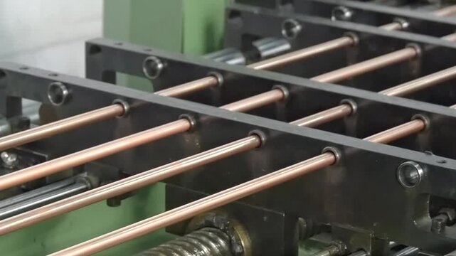Watch as skilled hands expertly maneuver copper rods through intricate machinery. The rhythmic clanking and whirring showcase the artistry of metal fabrication in a bustling atmosphere.