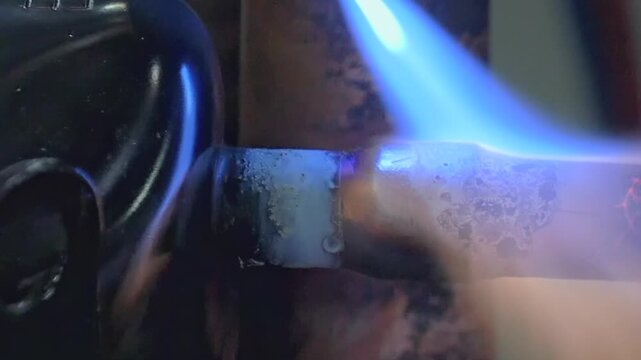 Hot fire melts metal joints inside a quiet workshop as molten glowing copper blends seamlessly with silver solder in a display of industrial skill and heat transformation during the late evening hours