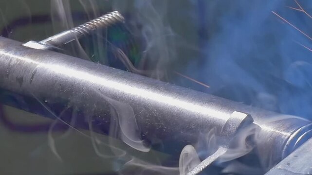A close-up view captures an industrial argon welding robot skillfully joining metallic pipes. Sparks fly, and smoke swirls as technology and craftsmanship unite in this dynamic process.