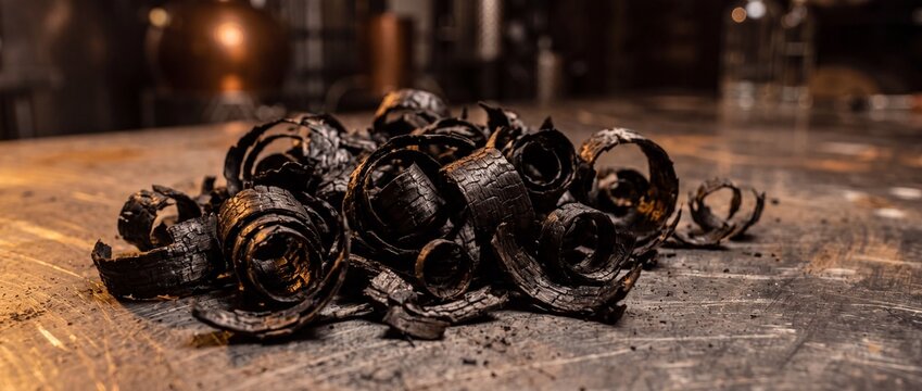 Toasted oak wood shavings pile up on metal workbench of winery cooperage providing smoky aroma notes for aging high quality spirits