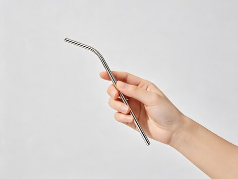 Hand holding a reusable metal straw on white background