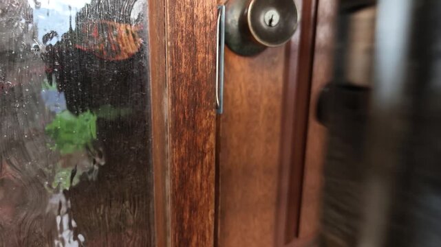 Close-up of a hand using keys to unlock a metal security gate and then a wooden front door. Home security and entryway concept