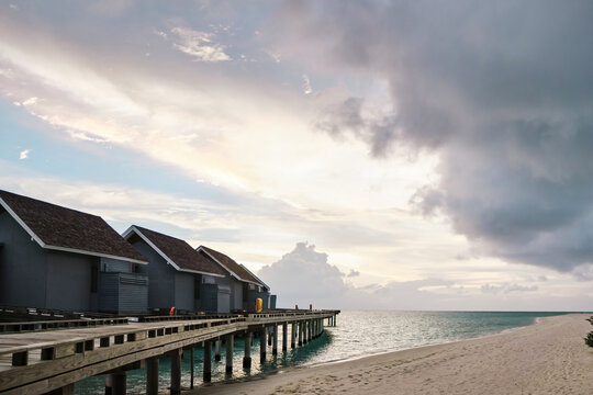 Overwater bungalows on a wooden pier at sunset on a beach in a beach