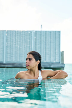 A white woman relaxes by the edge of a swimming pool