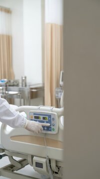 Medical staff operating hospital bed control panel with gloved hand for hospice and palliative care poster background and patient room design