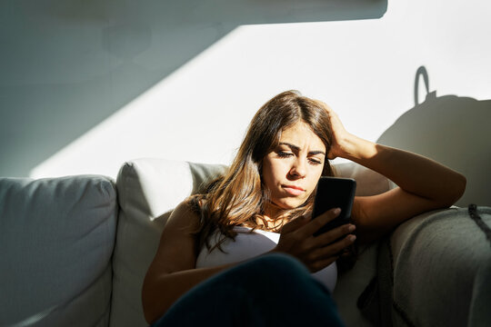 White Woman sitting on a sofa using a smartphone at home in Iceland