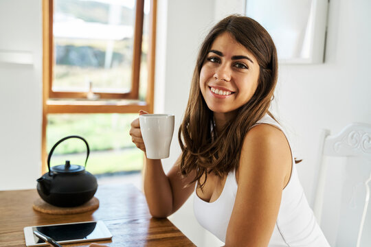 A young white woman enjoying tea in a bright indoor setting