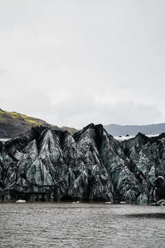 A melting glacier with ice peaks and volcanic ash in a glacial lake
