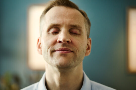 Portrait of middle aged Caucasian man closing eyes and smiling, practicing mindfulness and stress relief. Image represents mental wellbeing, suitable for healthcare marketing, close up