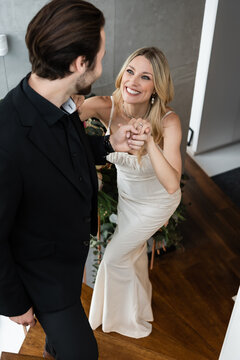 A blonde woman beams with joy as her partner proposes on a stairs 