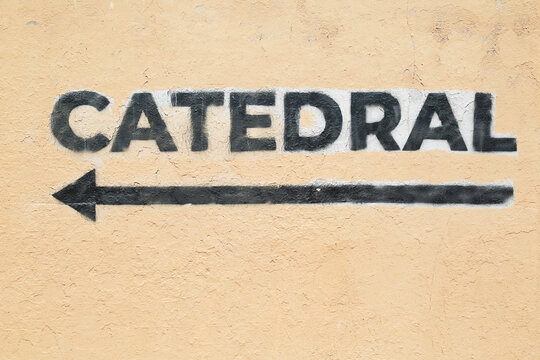 Directional sign painted on a wall where the word "cathedral" is written in Spanish