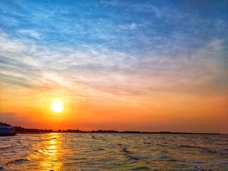 Fototapeta premium Golden sunset over the ocean with glowing reflections, gentle waves, and colorful sky creating a peaceful coastal landscape and tranquil nature background.