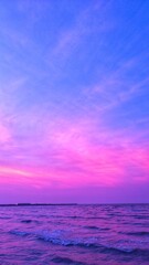 Fototapeta premium Vibrant purple and pink sunset over a calm ocean horizon, creating a dreamy seascape background with dramatic clouds and colorful twilight reflections.
