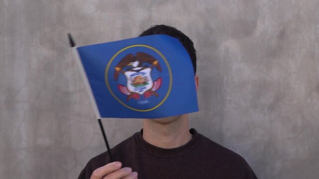 Male adult waving classic Utah state flag. Slow motion.