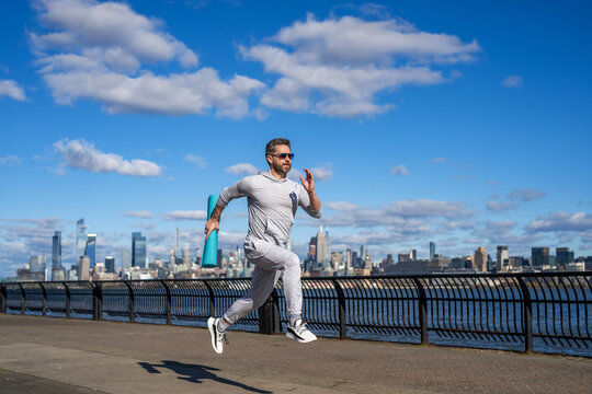 Man in sport outfit training running. Running man in Manhattan. Fast male runner. Morning sport workout jogger run in New York. Jogger run at sport training. Sportsman jogger running with fitness mat
