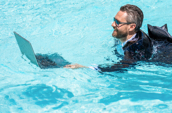 Remote working. Summer business vacation. Funny crazy businessman rest in formal wear in pool. Businessman in suit with laptop in swimming pool. Crazy business man summer vacation. Work on trip