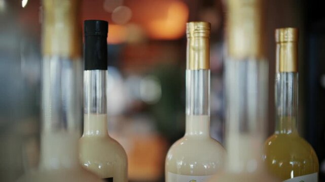 Glass bottles of creamy liqueur arranged on shelf in restaurant interior.