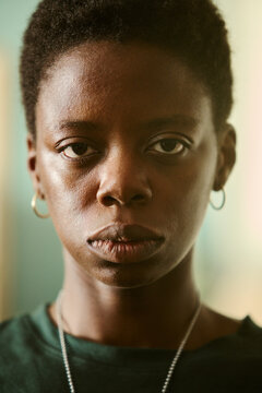 Portrait of young African American woman looking directly at camera with serious expression. Close up shot representing mental wellbeing and diversity campaigns, vertical