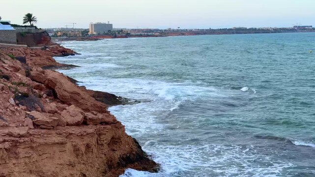 Coastal view of waves crashing against rocky cliffs on a overcast day in Orihuela Spain