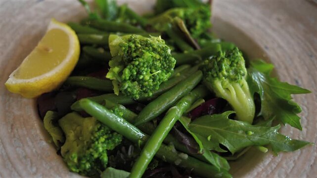Fresh green vegetable salad with broccoli and beans in ceramic bowl close up view.