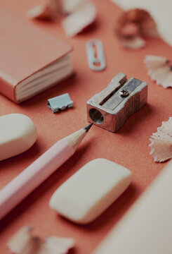 Pink pencil with eraser and sharpener on orange background