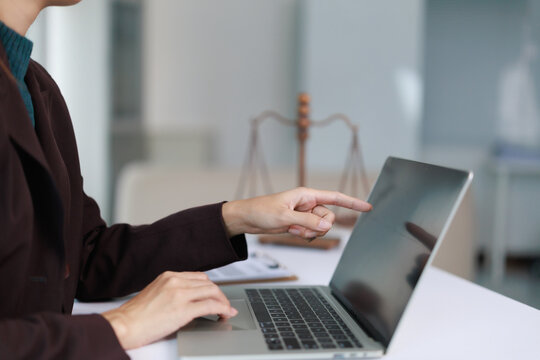 Legal professional using laptop and pointing at screen in office, working on legal documents and cases, researching law and justice online, modern legal services