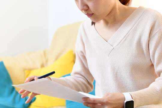 自宅のリビングで書類を書くアジア人の女性