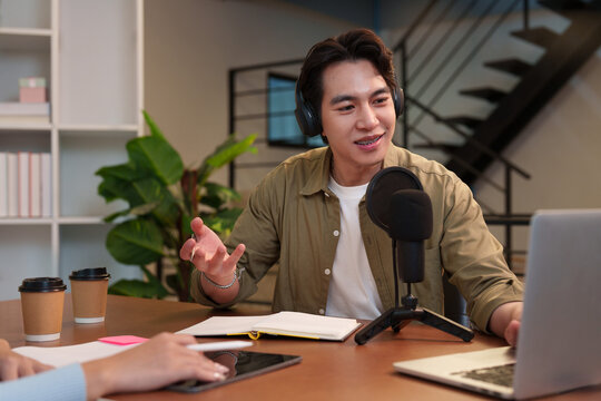 Asian male podcaster host speaking into microphone during recording