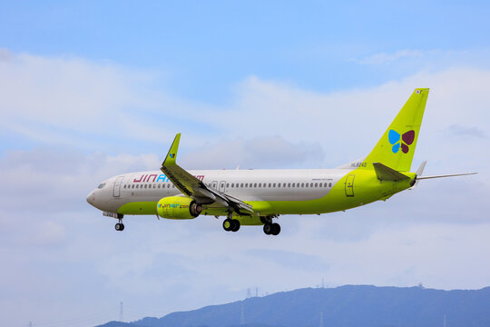 Fukuoka, Japan - August 8, 2026: Jin Air Boeing 737-800 (HL8242) descending on approach over a mountain backdrop